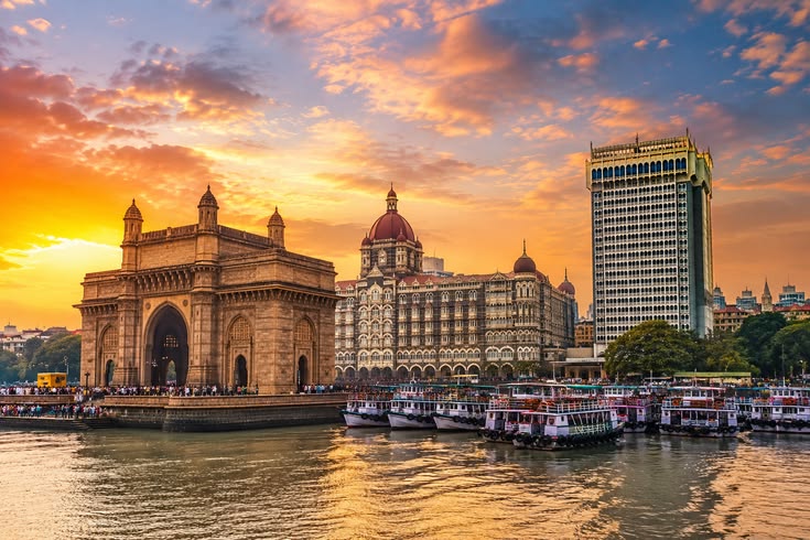 Mumbai Gateway of India, Taj Mahal Palace and waterfront with boats during a colorful sunset.